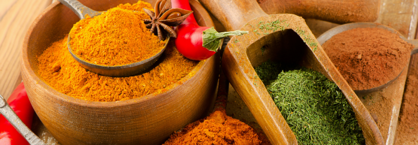 colourful ground spices on spoons on a wooden background