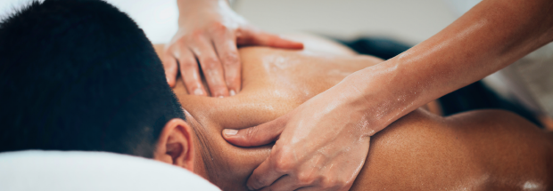 Man face down on massage table while his back is massaged