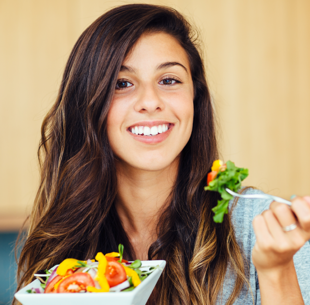 Young woman eating a healthy salad and smiling