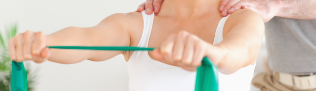 Woman using green resistance band under the supervision of an Osteopath