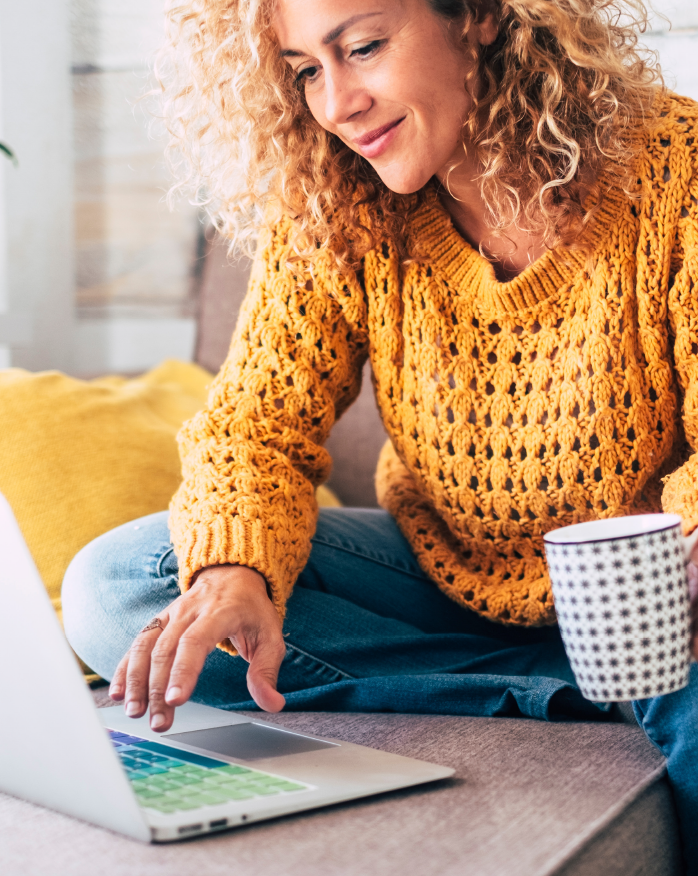 Young woman happily paying ATMS Membership Fees on her laptop while drinking coffee