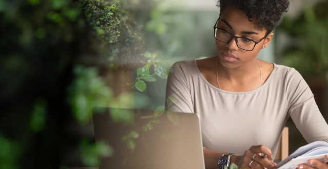 Young woman researching for a grant with foliage beside her