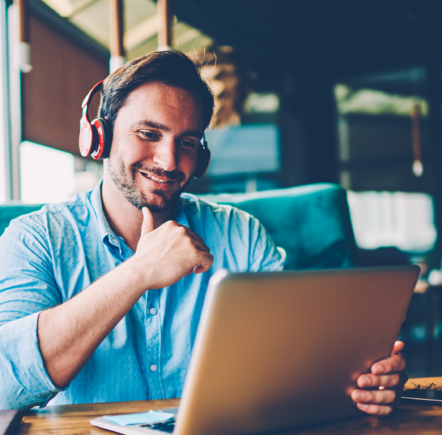 Male watching webinar recording on laptop with earphones