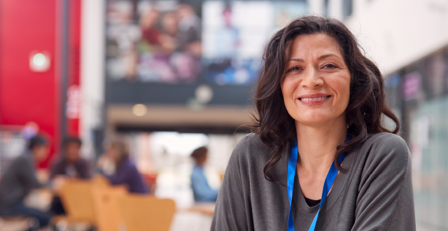 Teacher looking at viewer and smiling with students blurred in the background