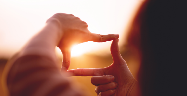 Person using hands to frame the sunset on horizon symbolising sponsor in spotlight