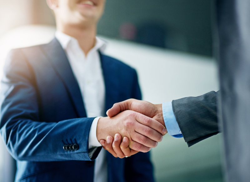 Two business people in suits shaking hands.
